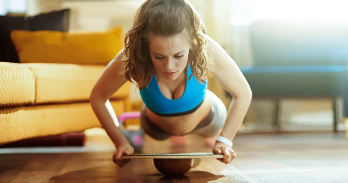 Woman is having a hard workout using a wooden wobble balance board